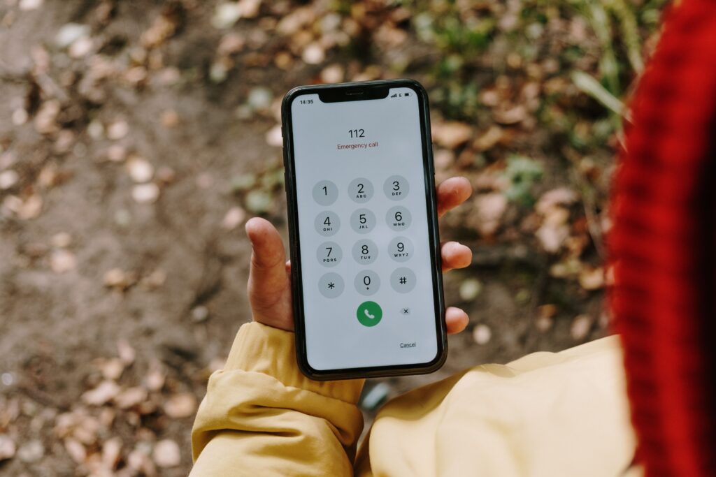 Smartphone displaying emergency assistance details for a Nigerian emergency abroad alongside a passport.