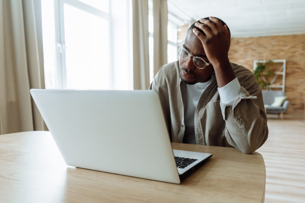 A frustrated professional sitting at a desk looking at a rejection email on a laptop screen while searching for english jobs Europe